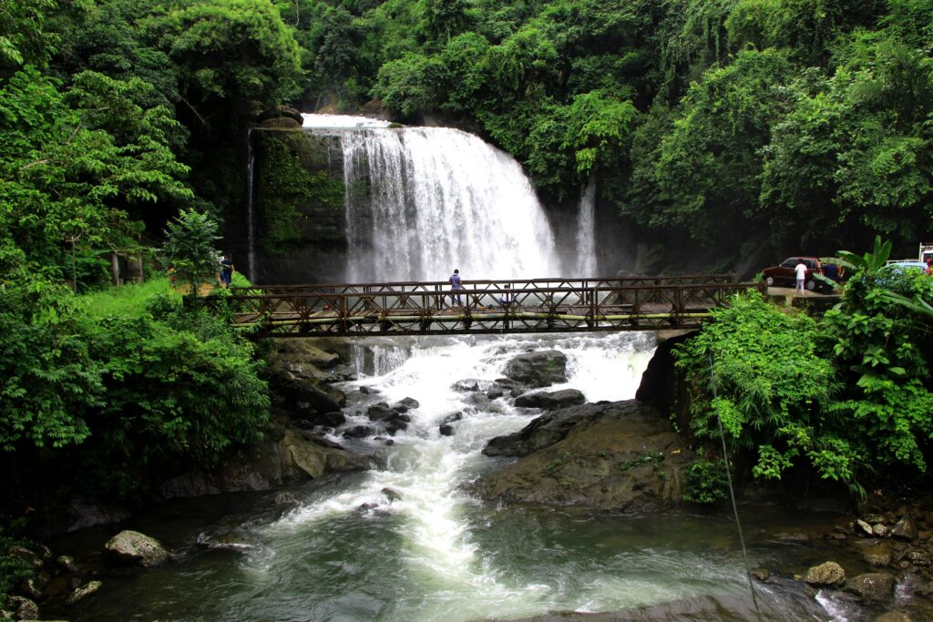 Explore the beautiful waterfalls of Dawki amidst lush greenery, showcasing nature's serene beauty.
