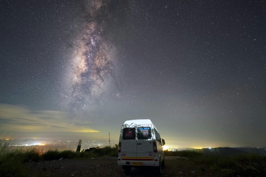 Stunning view of the Milky Way over a van under the night sky in Meghalaya, India, highlighting the beauty of the cosmos.