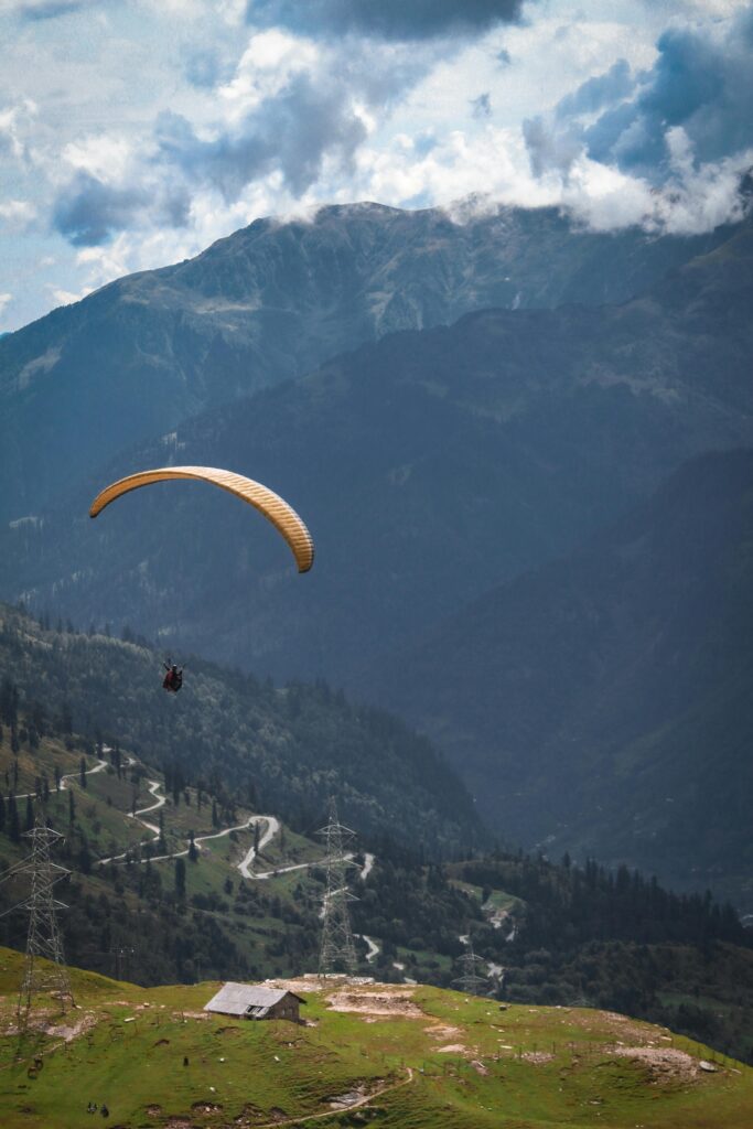 Experience the thrill of paragliding over picturesque hills and valleys in Manali, India.